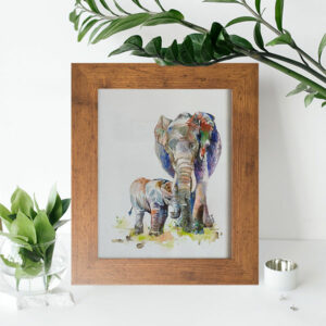 Elephant and calf watercolour painting framed in mid-brown wooden photo frame on a table